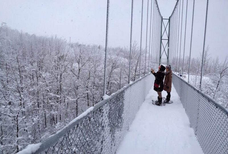 Snowshoeing across the suspension bridge at the Scenic Caves Nordic Centre - Winter hiking